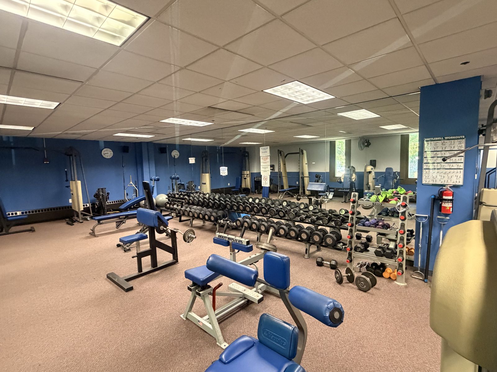 The strength area: dumbbell racks, benches, and kettlebells.